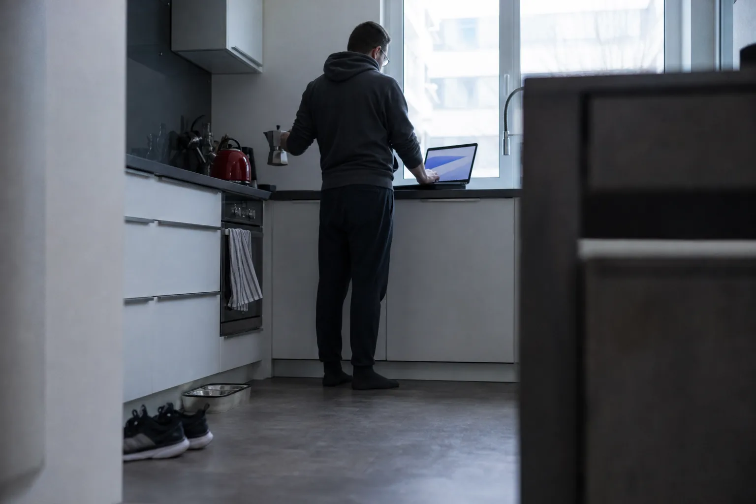 Engineer checking overnight jobs on a laptop at a kitchen counter before work