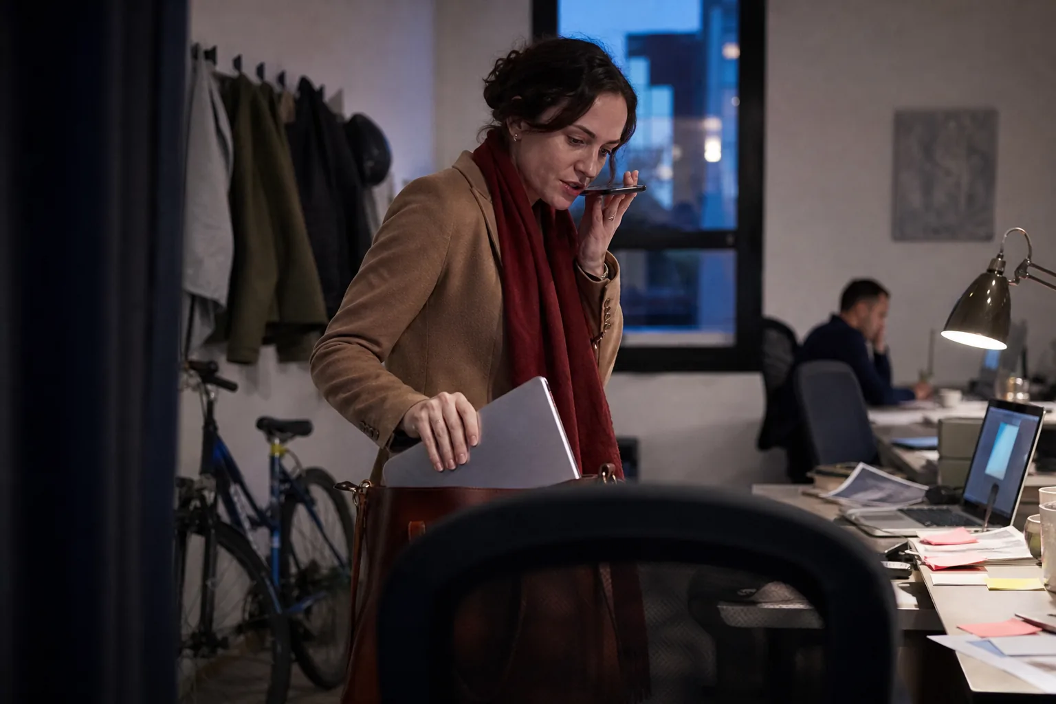 Sales manager dictating a weekly schedule into her phone while packing her bag at the end of the day
