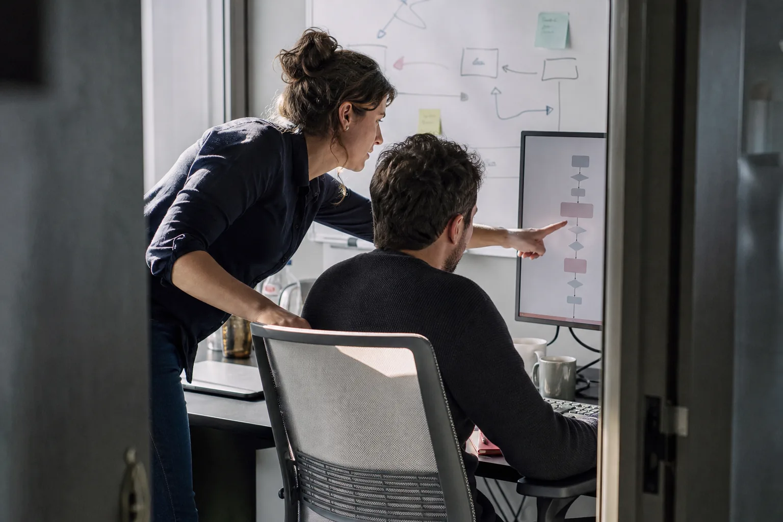 Two colleagues reading the step by step log of a finished run on a large monitor